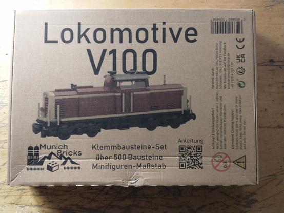 Cardbord box  of a "MunichBricks" V100 locomotive (german diesel engine) with a photo of the acutal brick model on the front.