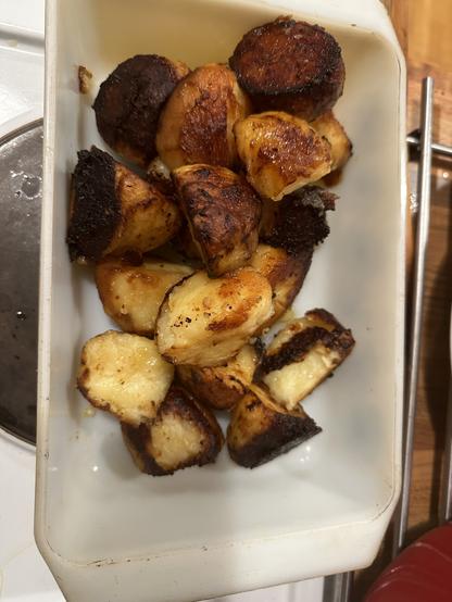 Marmite roast potatoes in a white glass dish.