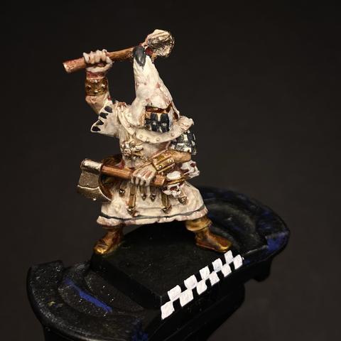 Painted miniature figure of a fantasy character in robes wielding a hammer and books, standing on a black base with white markings.