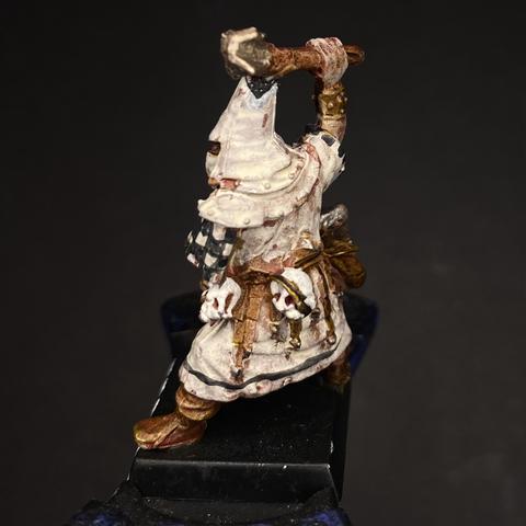 A painted miniature figure of a fantasy warrior in ornate armor holding an axe, displayed on a stand.