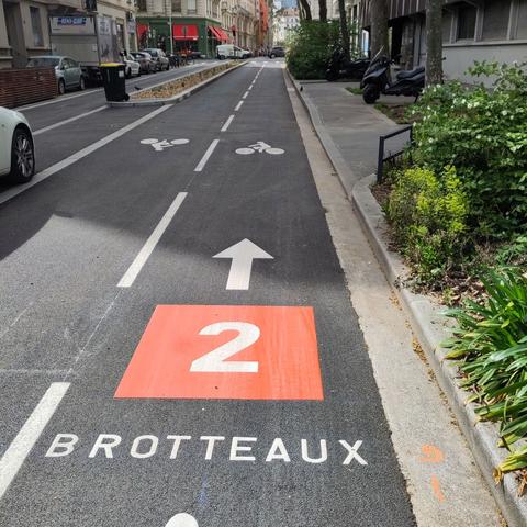 photo d'une piste cyclable avec un 2 blanc sur fond rouge, et noté dessous : Brotteaux