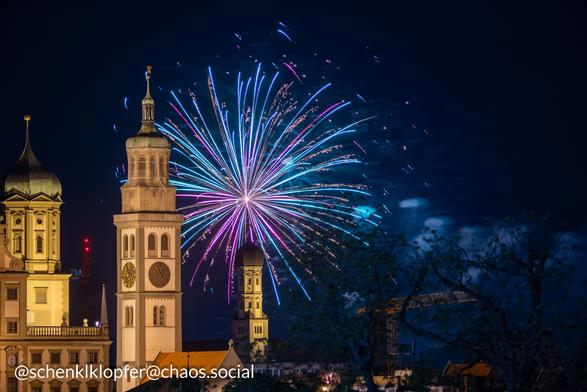 Vordergrund: Beleuchtets Rathaus
Hintergrund: Langzeitbelichtung eines Feuerwerks. Farben Rot und Blau