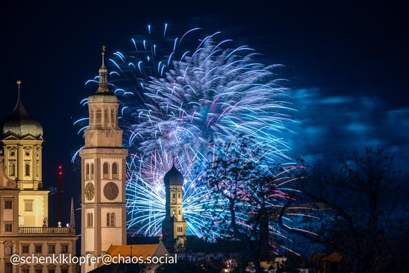 Vordergrund: Beleuchtets Rathaus
Hintergrund: Langzeitbelichtung eines Feuerwerks. Farbe Blau