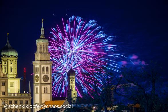 Vordergrund: Beleuchtets Rathaus
Hintergrund: Langzeitbelichtung eines Feuerwerks. Farben Rot und Blau