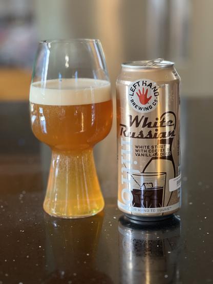 The stout is now settled and golden in color with a white head. The can shows a bowling pin and a cup of iced coffee