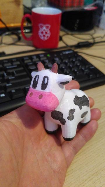 A photograph of a 3D printed model of Spot the cow. The model was printed using white filament and then coloured (spots and eyes etc were drawn on) with markers.
