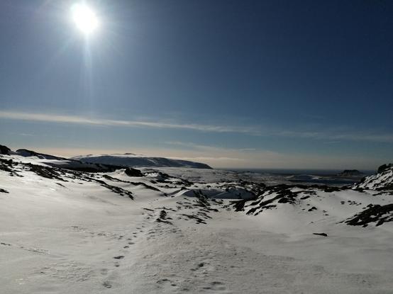 Vue d'une partie de la péninsule du Reykjanes en direction du sud avec une météo ensoleillée. Des traces de pas sur un sentier pédestre encore largement enneigé.