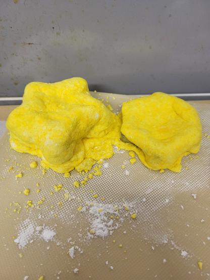 Gooey yellow blobs. The left one is slightly bigger than the other. They are vagely star shaped. Side by side, they lie flat on a textured surface.