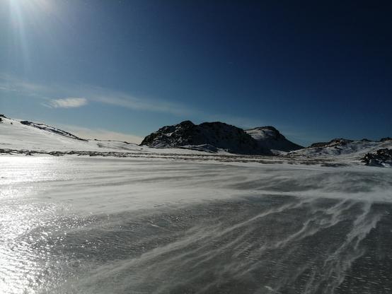 L'arnarvatn gelé sur lequel file de fines bandes de neige au ras de la glace