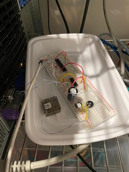 Photo of a breadboard with a circuit connected to the back of a server.