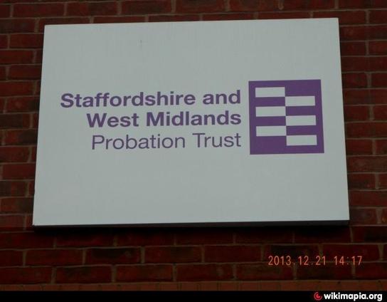 Photo of a sign on a brick wall stating “Staffordshire and West Midlands Probation Trust” in purple writing on a white background with a ‘checkerboard’ design in purple on the right of the writing.