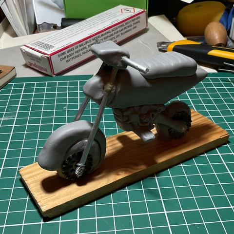 The model now has sculpey on top of it. It has a seat, a little engine and a snail shell for a front wheel.