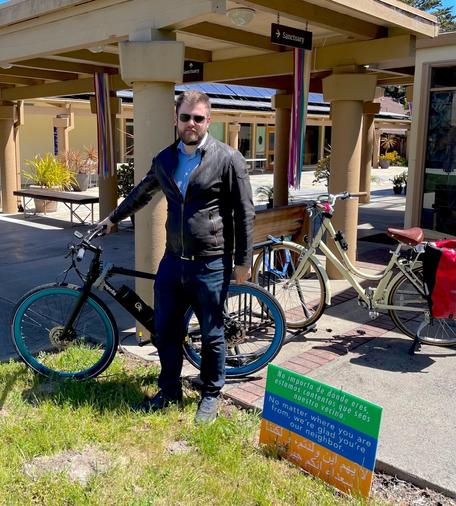 A man stands alongside his bicycle next to a bike parking rack, where another bike is parked, at First Presbyterian Church of Monterey.