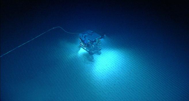 Underwater photo of a robotic vehicle exploring sandy sea floor