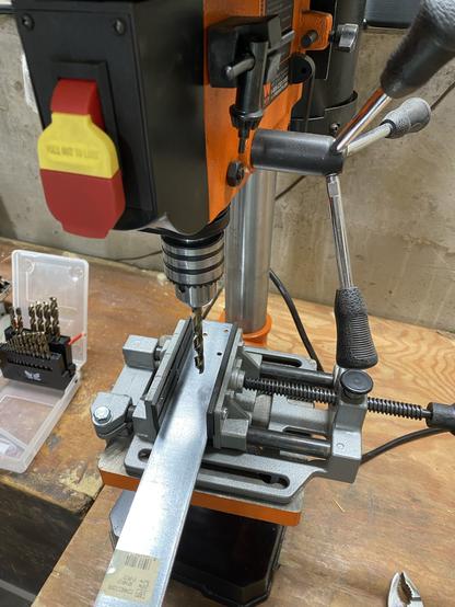 drill press and metal bar set up to add an 8mm hole to said bar and hopefully not also to drill press