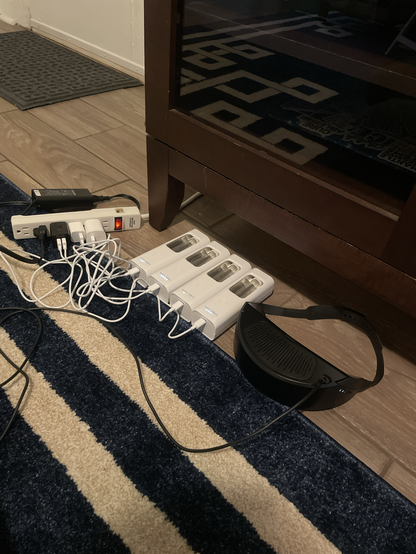 Four NUKIT torch portable UV lights and a Respiray wearable HEPA filter charge while plugged into a very busy surge protector extension cord.