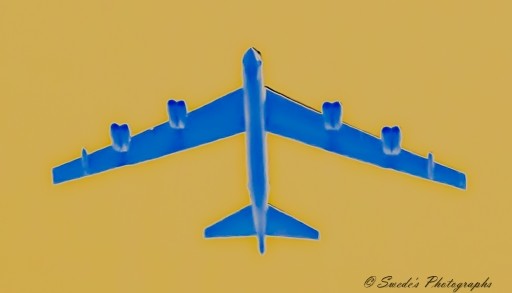 "The image depicts a digitally altered view of a B52 Stratofortress flying directly overhead. It has been colored blue, which appears to be a digital enhancement. The B52 features four pairs of engines attached to its wings, characteristic of this type of bomber. The background is uniformly yellow, contrasting with the blue color of the plane. This background also seems digitally altered. At the bottom right corner, there’s a copyright notice attributed to “Swede's Photographs”. Please note that this image is an artistic representation and not a standard photograph of an actual B52 Stratofortress." - Copilot with edits