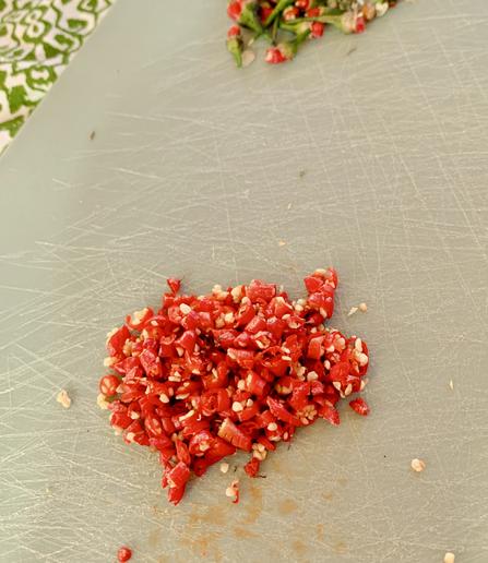 Freshly chopped piripiri chilipeppers on a cutting board.