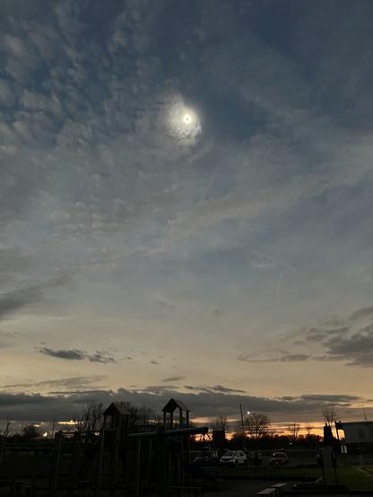 A dark sky during an eclipse, with glimpses of the ground.