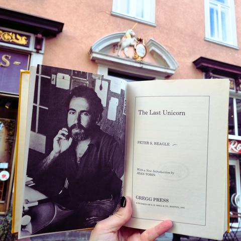 Holding Peter S. Beagle's book The Last Unicorn in front of the Universitätsapotheke Göttingen, which bears the traditional sign of a unicorn
