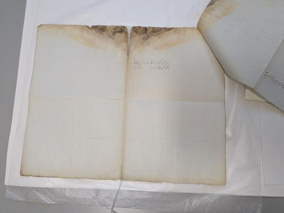 A4+ size paper, bluish in colour. Discolouration at the centre fold line. A brown/black mottled area at the edge.