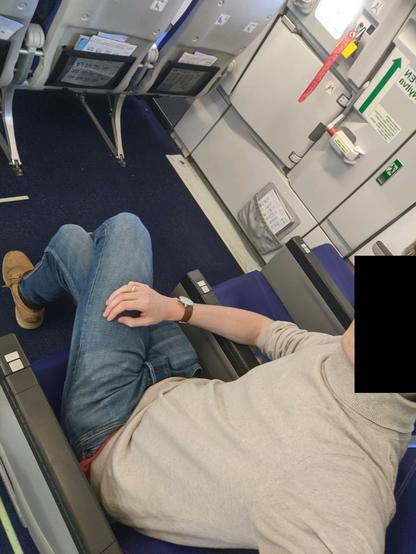Selfie (visage floutté) où l'on voit que j'ai toute la place d'étendre mes jambes, étant situé devant les portes d'évacuation