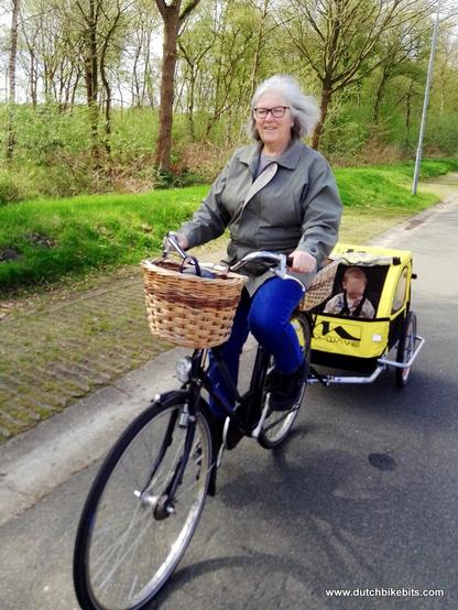 Judy riding along pulling a bicycle trailer with our grandson inside.