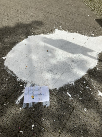 What seems like an entire bucket of paint was spilled on the sidewalk. A note written in German accompanies it “Vorsicht! Frisch Gestrichen” (Warning: Freshly painted)