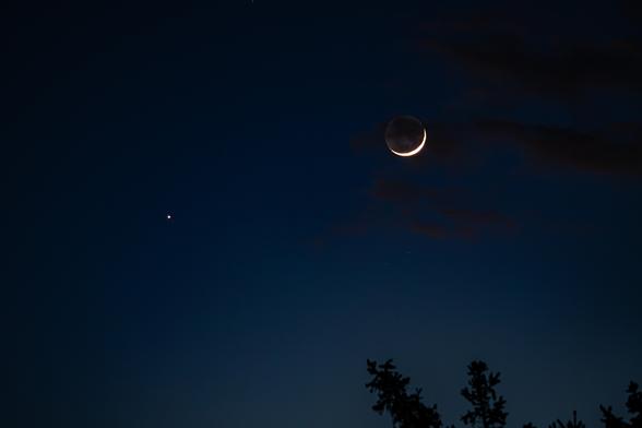 Photo of a night sky with a crescent Moon and a few stars.