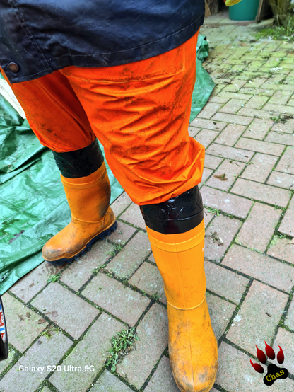 closeup on person wearing hi vis trousers and orange rubber boots, boots and trousers taped together with a few rounds of duct tape