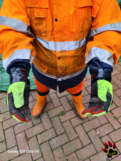 closeup on a person wearing hi vis raingear and rubber boots, goved hands extended, gloves and jacket armes taped together with duct tape