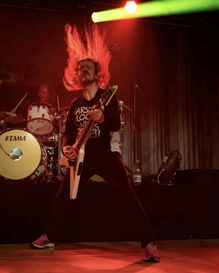 Vito wirft seine Haare in die Luft auf der Bühne - im Hintergrund Wolfram an den Drums.