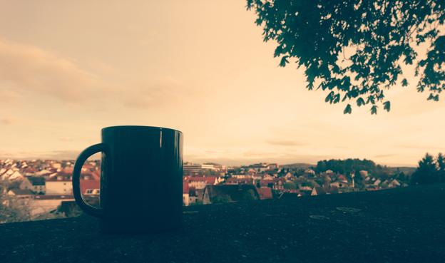 Eine Tasse auf einer Mauer mit der Stadt im Hintergrund.