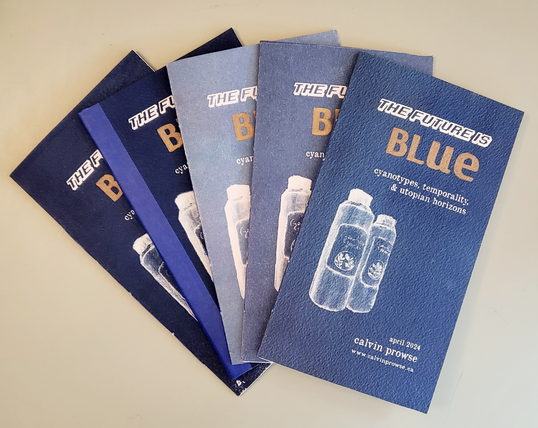 A stack of five zines printed in varying hues of blue.