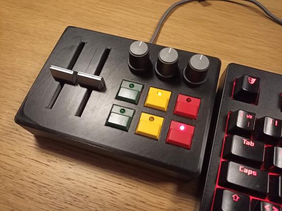 Black 3D-printed box with 2 sliders, 3 pots and 6 buttons with integrated LEDs.