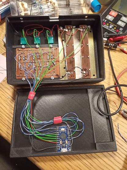A taken apart electronics box with a PCB were some resistors can be seen, and some components with a bundle of wires connecting everything to the micro controller board in the base of the box.