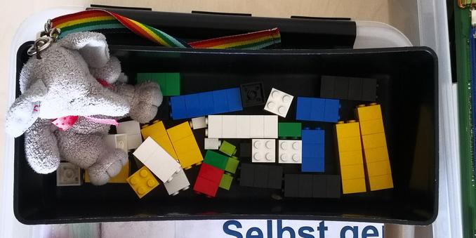 Draufsicht: Elefanty Elfi hockt in einer rechteckigen Schale mit quadratischen Klemmbausteinen: Sie nimmt ein Bällebad (hat sie gesagt).