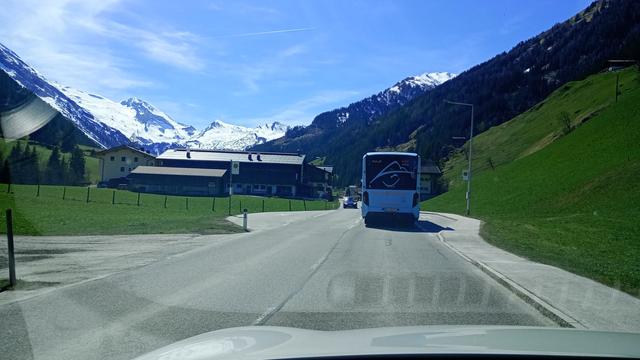 Straße nach Hintertux, vor uns fährt eine blauer eBus (MAN eLion). Links und Rechts grüne Felder und Böschungen, im Hintergrund sieht man den Gletscher