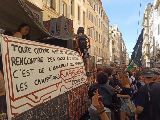 Manifestation de teufers à Marseille, rue de Rome. Sur la pancarte d'un camion il est écrit "Toute culture naît du mélange, de la rencontre, des chocs. À l'inverse c'est de l'isolement que meurent les civilisations. Rave on. Octavio Paz"