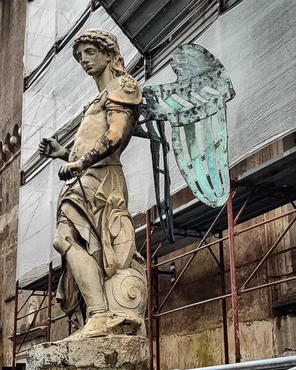 A photo of the 5th statue of the archangel Michael on display at the Castel Sant'Angelo in Rome, showing it's tarnished bronze wings.