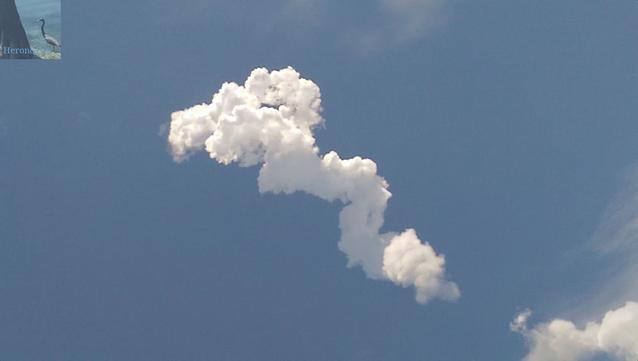 A photograph of a white cloud against a blue sky. The cloud seems to twist and turn as it goes from the lower right corner to the upper left.
