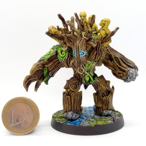 Painted miniature of a magically animated tree. It has glowing blue eyes, and a stone fist and stone feet. On top of it sits 4 yellow alien-like creatures. It is standing on a small stream with rocks and ferns around it.