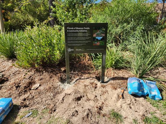 A sign in a garden bed.
