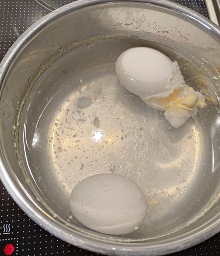Two eggs getting boiled. One of them has exploded.