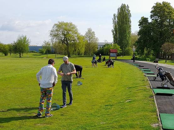 wir sehen eine Golfplatz Drivinge Range, auf der sich diverse Spieler warm spielen und Trainieren