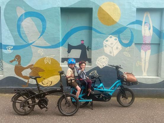 Tern Vektron and Tern GSD e-bikes parked in front of a mural.