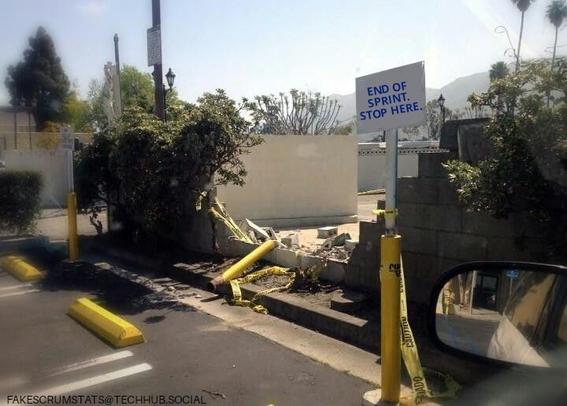 Photo of a wall in a parking lot that looks like a car broke through it.

There is a sign that reads "End of sprint. Stop here."