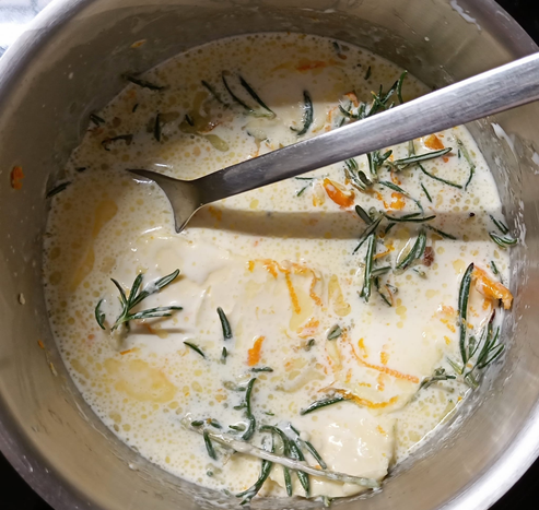 in einem Topf köchelt die Sahne mit Rosmarin und Orangenschale