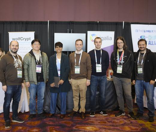 Seven Igalians in front of the Igalia's booth E28 at the OSS-NA/EOSS. From left to right: Adrian Pérez, Changwoo Min, Rakhi Sharma, Samuel Iglesias, Alejandro Piñeiro, Mario Sanchez and Lauro Moura.