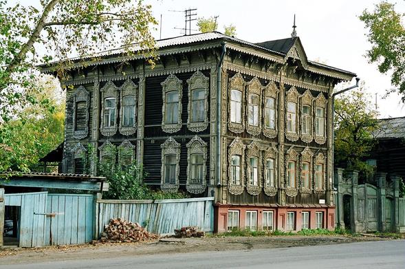 A big, two-store wooden house with lots of decoration on the facade.